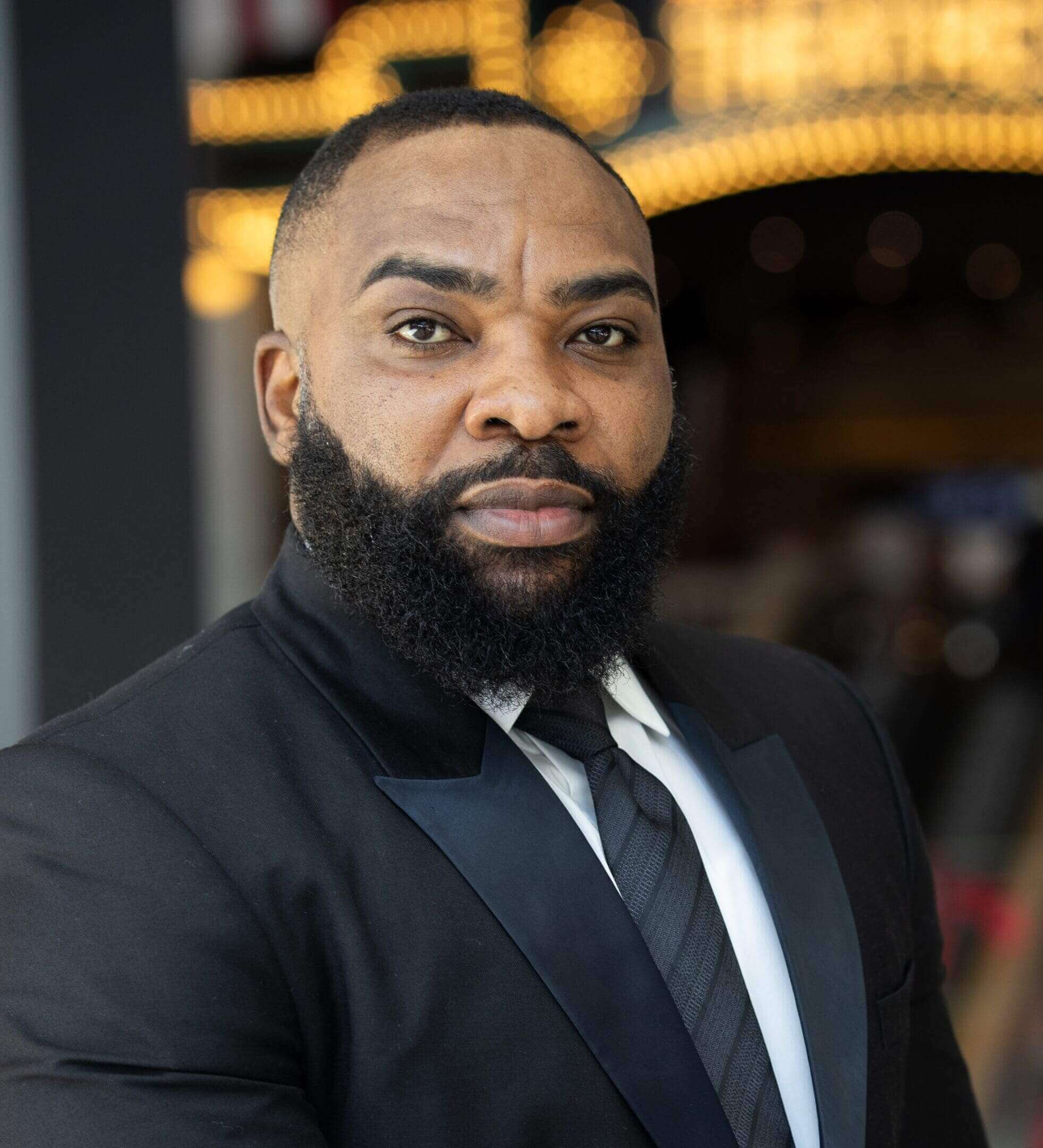 Man in suit with beard, serious expression.