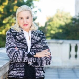 Woman in striped jacket outdoors, smiling confidently.