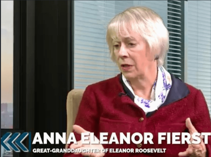 Woman speaking in a red jacket, indoors.